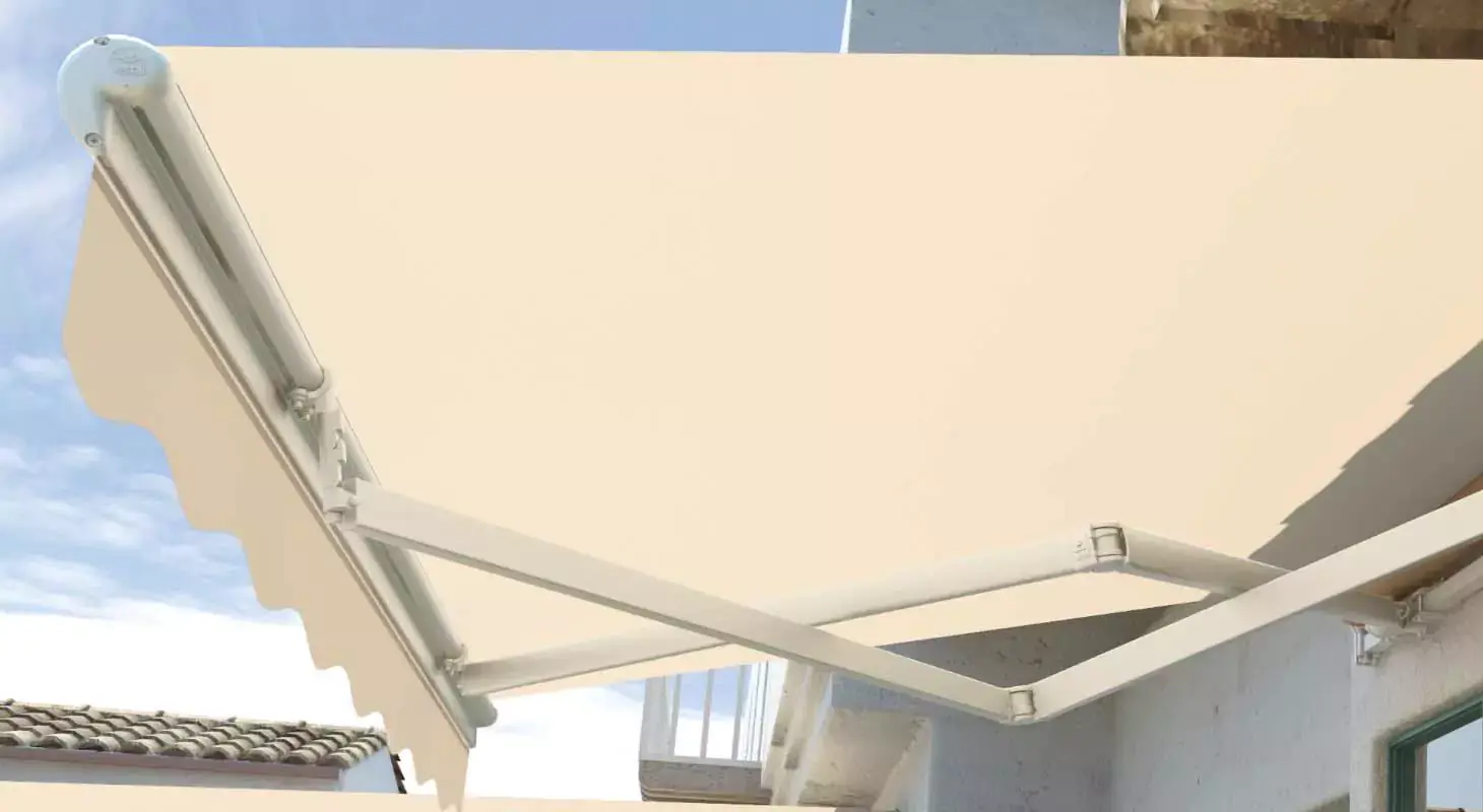 Bež tenda z vidnimi pregibnimi rokami, nameščena nad teraso z belo fasado in zelenimi okni.