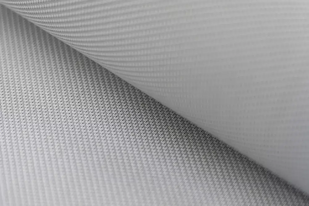 Povečan detajl svetlosive tehnične tkanine z vidno teksturo, primerne za senčila ali tende.