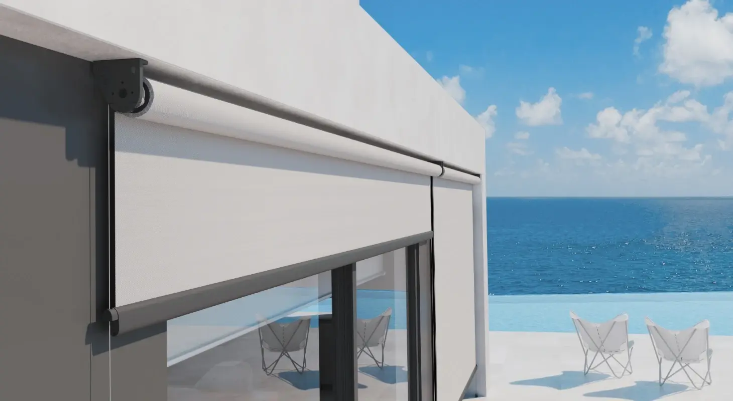 Moderna bela screen rolo senčilo na fasadi obmorske hiše z razgledom na morje in teraso z ležalniki.